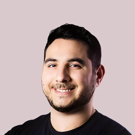Smiling man with short dark hair and beard against a light background.